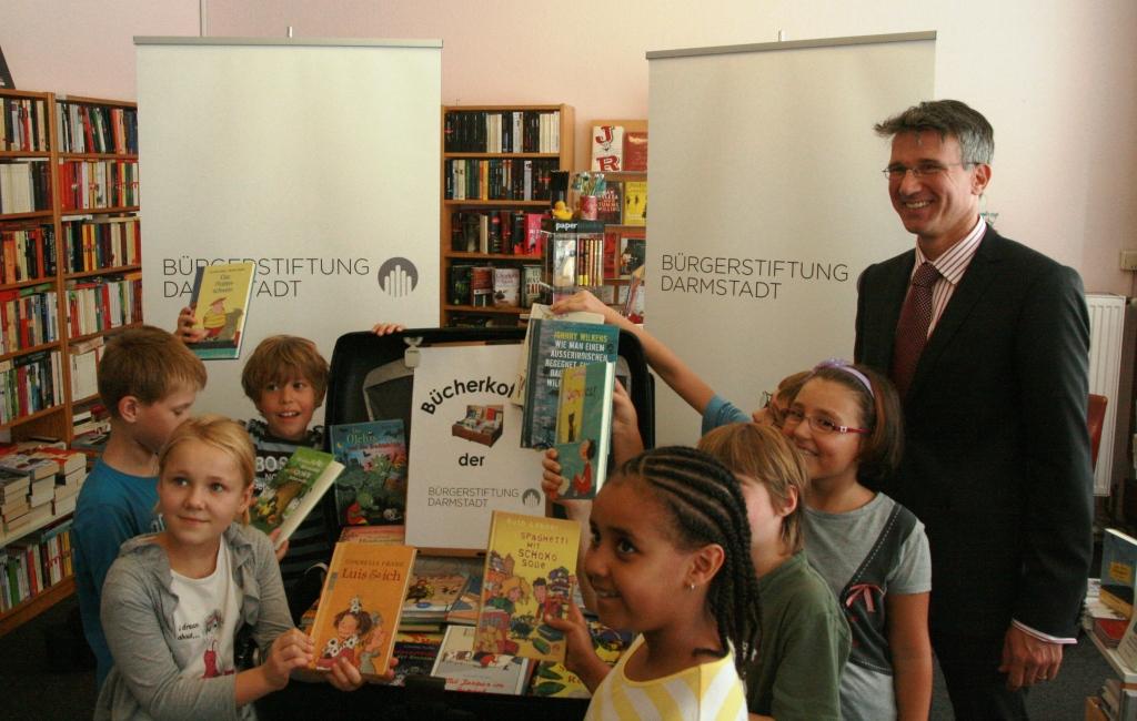 Der Vorstandsvorsitzende der Bürgerstiftung, Dr. Markus Hoschek, übergibt den ersten Bücherkoffer an die Klasse 3a der Heinrich-Heine-Schule. (Foto: Bürgerstiftung)